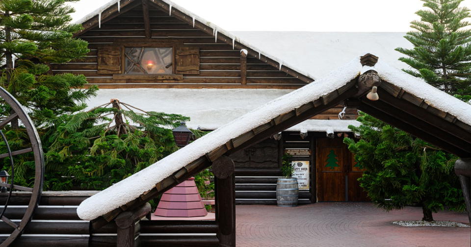 An exterior photo of North Woods Inn, showcase its snowy roof and log cabin style.